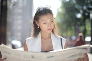 A woman reading a newspaper staying updated on SEO